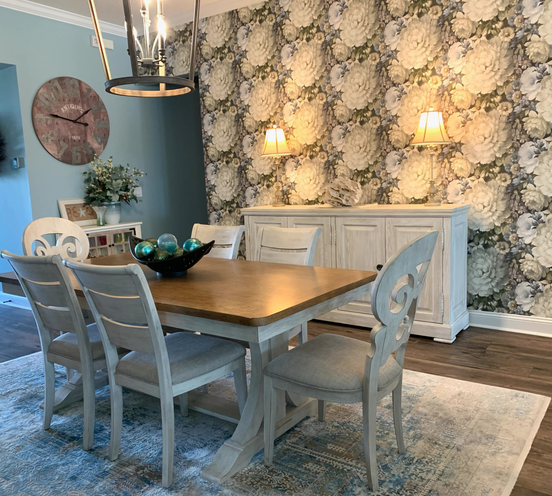 Elegant dining room with hydrangea wallpaper, a wooden dining table, and soft blue upholstered chairs