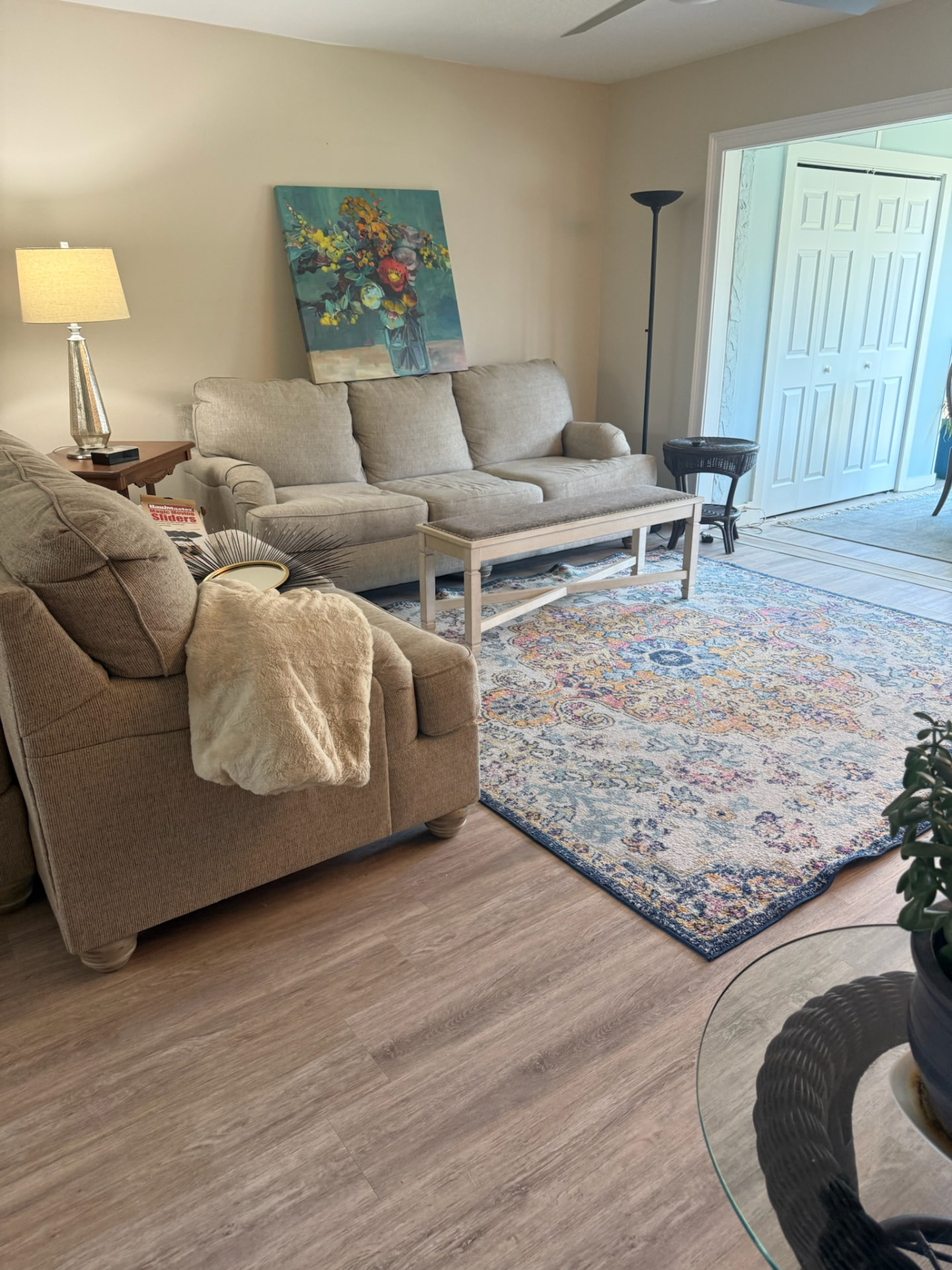 Transitional living room styled by Madeline’s Chic Interiors with a grey sofa, colorful floral artwork, and a navy area rug